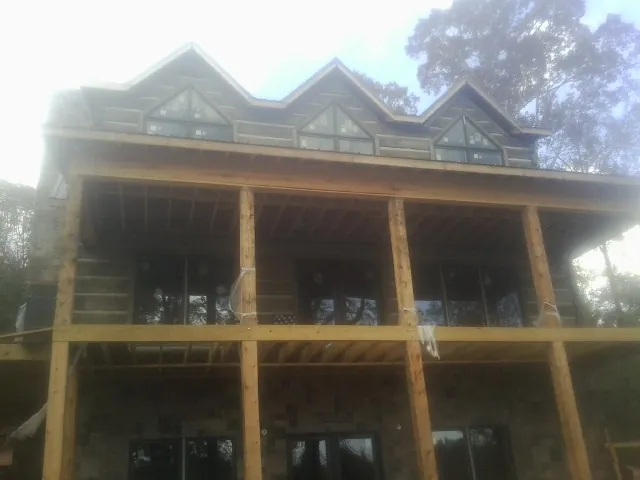 Dormers and porch framing on a large log home under construction — Roof Coating work by our crew in Kenton