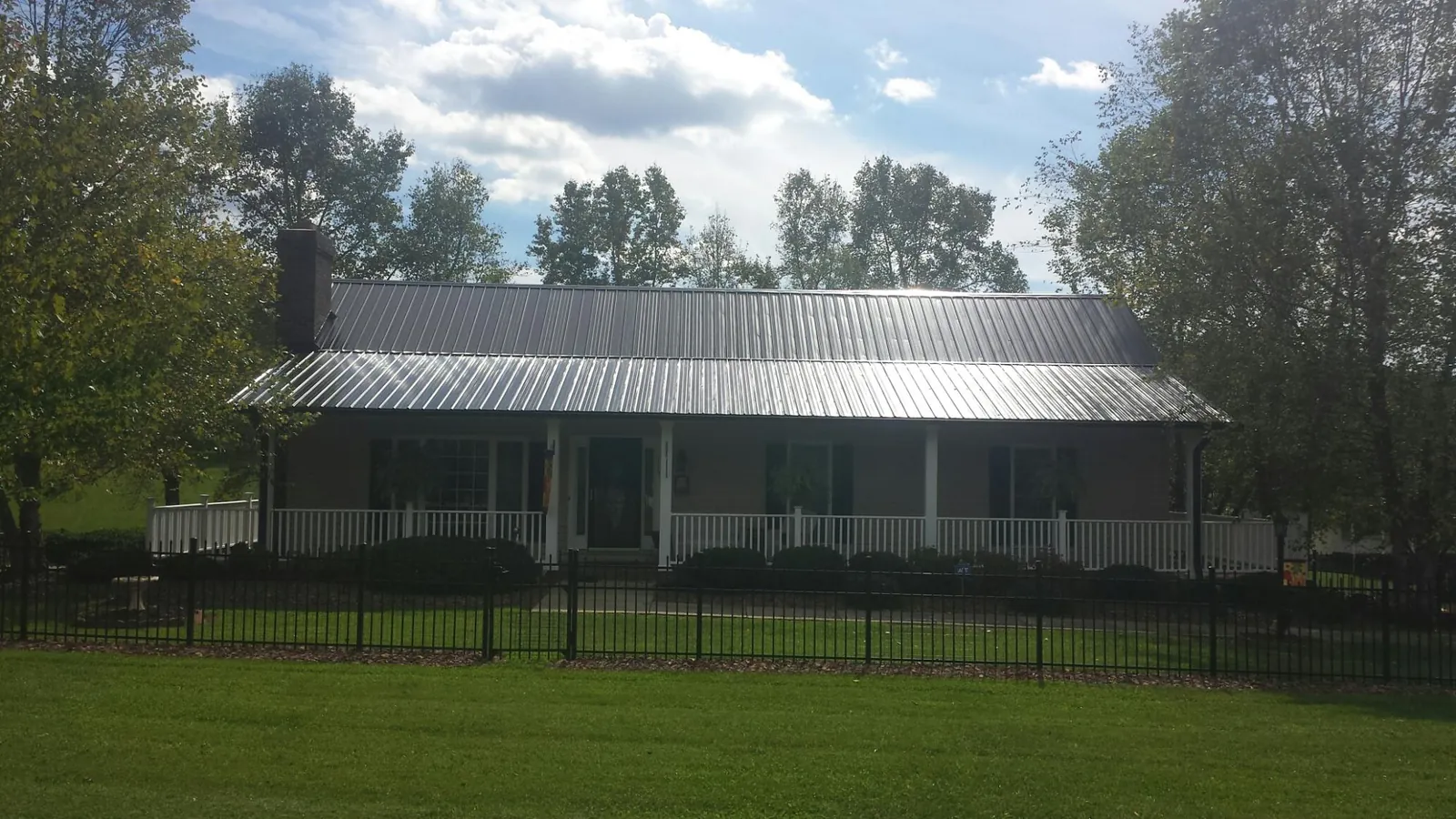 Gray metal roof on a brick ranch with a full width front porch — Gutter Guard Installation work by our crew in Kenton